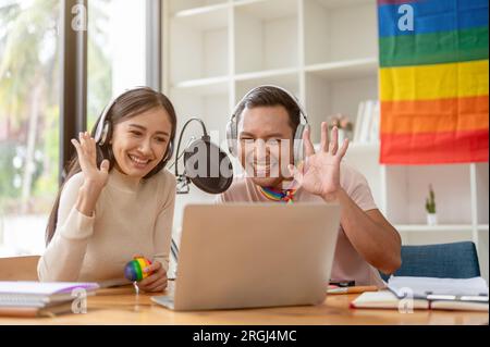 An attractive and happy Asian gay man enjoys reading comments online, talking, and streaming live podcasts online with his female colleague in the stu Stock Photo