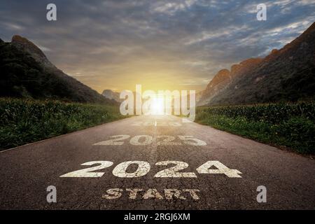 2024, the new year 2024 or the beginning of the concept of the word 2024, written on the road in the middle of the paved road with a sunset mountain b Stock Photo