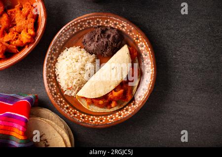 Chicharron en salsa roja. Pork rinds stewed in red sauce accompanied by rice and refried beans. Traditional homemade dish very popular in Mexico, this Stock Photo