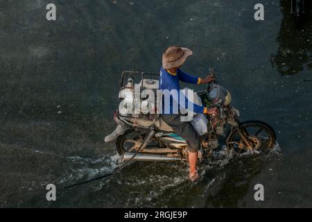 People ride a motorbike through floodwater caused by rain and high tide ...