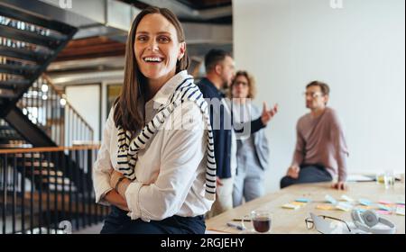 business woman in her 30's looking at the camera in a boardroom. business woman having a meeting with her team in an office. Female professional worki Stock Photo