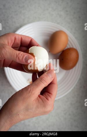 Caucasian female peeling hard boiled eggs closeup view from above Stock Photo