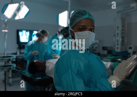 Portrait of african american female surgeon wearing surgical gown in operating theatre at hospital Stock Photo