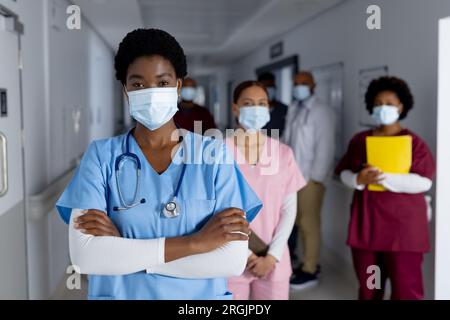 Portrait of diverse female doctors wearing face masks in corridor at hospital Stock Photo
