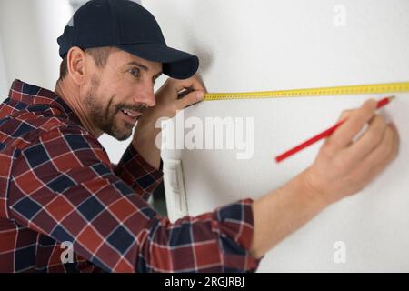 man measures a wall with a ruler Stock Photo