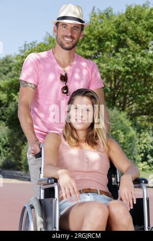 Disabled person walking having fun with friend in wheelchair on the ...