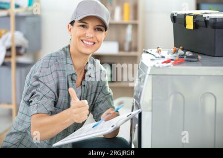 beautiful female plumber repairing washing machine Stock Photo