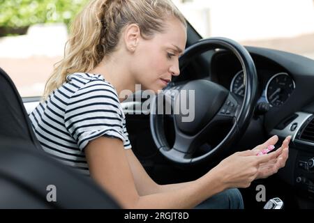 young woman taking pill while driving Stock Photo