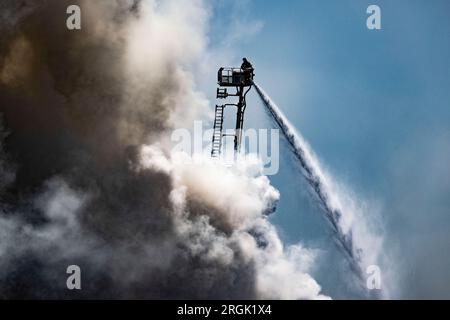 Duisburg, Germany. 10th Aug, 2023. Firefighters continue to extinguish the major fire in the port of Duisburg, which has been ongoing for hours on the scrap island. In the port on the scrap island, a fire broke out on Thursday, 09.08.2023 at a recycling yard with end-of-life vehicles. About 100 tons of scrap metal was on fire, said a spokesman for the fire department. Credit: Christoph Reichwein/dpa/Alamy Live News Stock Photo