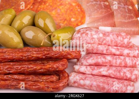 Full frame of appetizers of smoked sausages, sliced sausages with fat, olives. Close up. Stock Photo