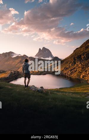 Adventurous young man enjoying the views of Anayet lakes and Midi d'Ossau peak at sunset. in the pyrenees Stock Photo