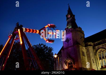 An illuminated fairground ride with Banbury Town Hall in the background, during the annual Banbury Michaelmas Fair Stock Photo