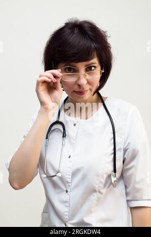 Woman doctor through glasses looks at the camera, close-up. Stock Photo