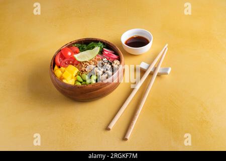 High angle of wooden bowl with slices of healthy tomato mango tofu and radish served with wakame salad and edamame beans with piece of lime on top nea Stock Photo