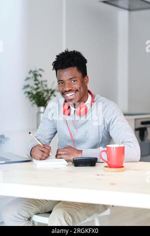 Content African American male financier with headset and notepad looking at camera while working in house Stock Photo