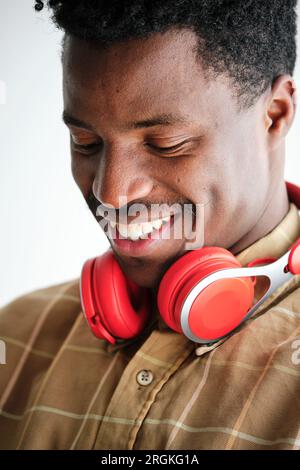 Young African American male in checkered shirt with contemporary headset looking down with toothy smile Stock Photo