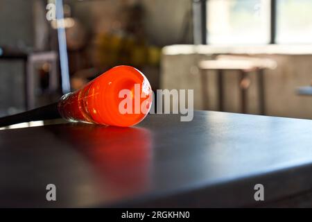 Heated glass mass on edge of pontil in process of making hookah vase at factory Stock Photo