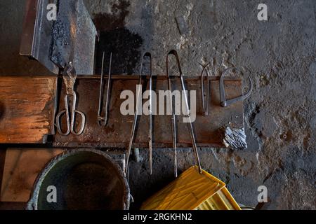 High angle of various glass making tools arranged on metal bench in workshop against weathered wall Stock Photo