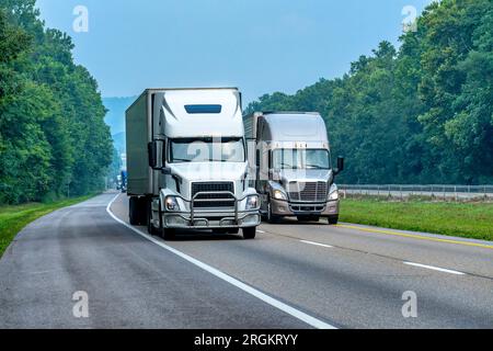 Horizontal shot of two semi trucks on the interstate with light traffic. Stock Photo