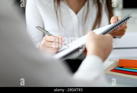 Close-up of people sitting in office and writing something Stock Photo