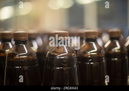 Bottles of carbonated drink in supermarket. Water in stock. Plastic bottles stand in row. Brown beverage container. Stock Photo