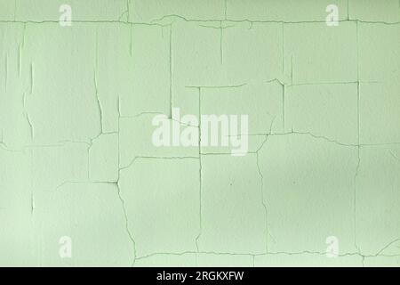 Cracks in paint. Old paint on wall. Fine mesh of cracks on surface. Green background. Stock Photo