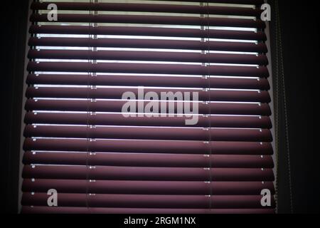 Blinds on window. Window in apartment. Closed blinds. Light through glass. Stock Photo