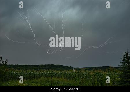 Whimsical branched lightning high in the sky over the hilly landscape of Transylvania, Romania. Stock Photo
