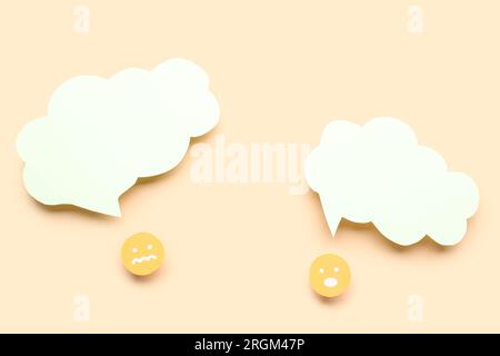 Paper faces with blank speech bubbles on beige background Stock Photo