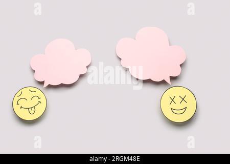 Paper faces with blank speech bubbles on grey background Stock Photo