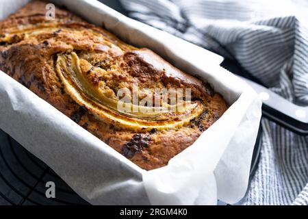 Freshly made banana bread with dark chocolate chips and sliced banana on the cooling rack Stock Photo