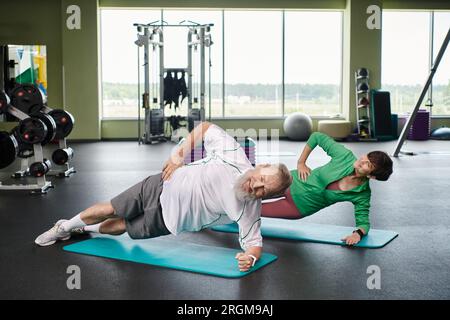 elderly man and woman doing side plank on fitness mats, active seniors exercising on in gym Stock Photo