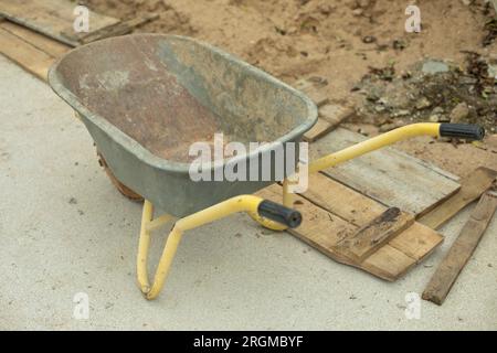 Sand cart. Transport at construction site. Transportation of materials. Yellow handles. Steel boiler for cement. Stock Photo