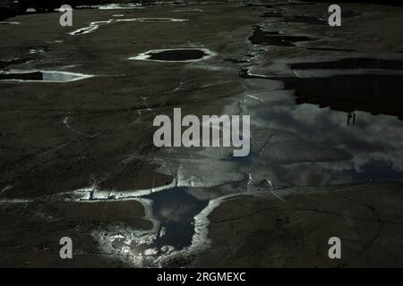 Puddle on pavement. After rain. Road in pits. Reflection of sky in puddle. Stock Photo