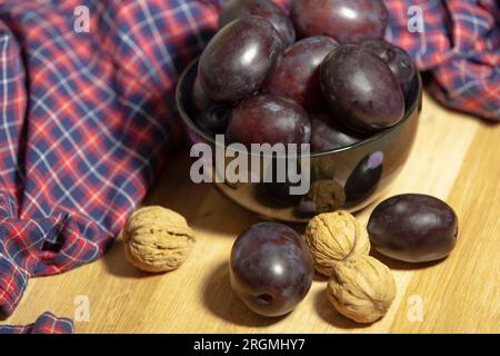 Black plums. Raw prunes in a bowl and walnuts. Stock Photo
