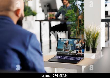 Project manager collaborating remotely with coworkers in online meeting using laptop in business office. Executive discussing start up with company employees in videocall Stock Photo