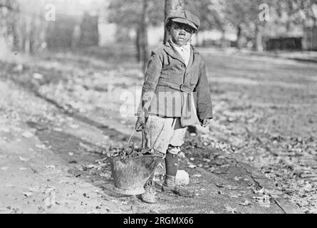 Young African American boy carrying a bucket of coal ca. 1909-1932 Stock Photo