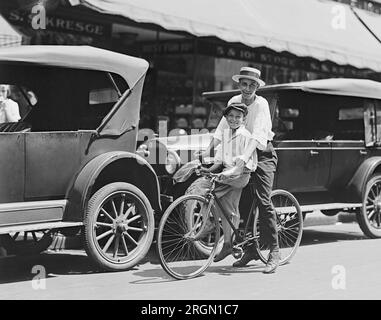 Two boys on a bicycle smile for the photographer, in front of an S.S. Kresge store in Washington D.C. ca. 1924 Stock Photo