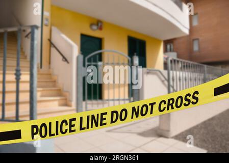 Yellow crime scene tape blocking way to house outdoors Stock Photo