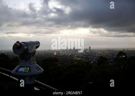 Snrise view over the city from the lookout at Mt Coot-Tha over Brisbane, Queensland, Australia, with a telescope in the foreground Stock Photo