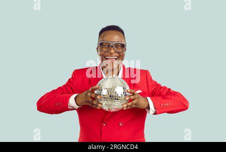 Cheerful energetic dark-skinned man holding disco ball is preparing for holiday party. Stock Photo