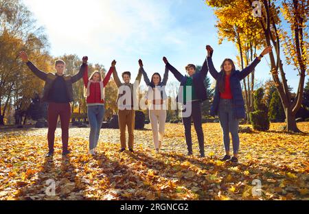 Happy friends standing together raising their hands in park Stock Photo