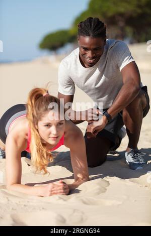 young couple doing fitness on the sunny beach Stock Photo