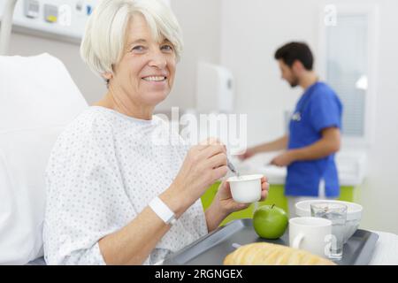 senior woman lying in bed and drinking tea in hospital Stock Photo