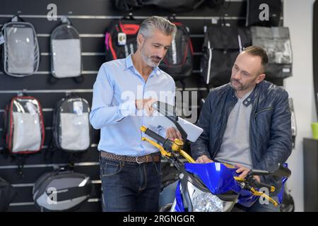 man motorcyclist chooses motorcycle accessories in store Stock Photo