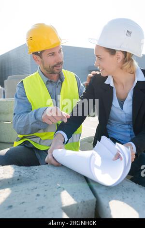 female inspector and worker discuss about blueprints on construction site Stock Photo
