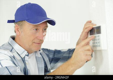 mature male worker installing alarm system Stock Photo
