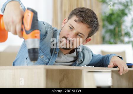 worker drills a hole when assembling furniture Stock Photo