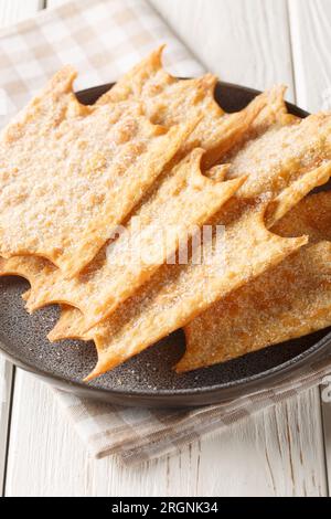 Oreillettes deliciously light and crisp pastry fritters closeup on the plate on the wooden table. Vertical Stock Photo