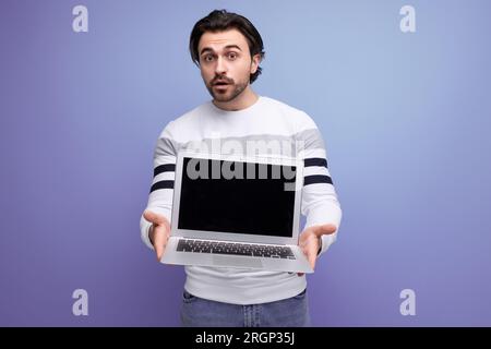smart european young guy with chic black hair shows promotional offer on blank screen Stock Photo